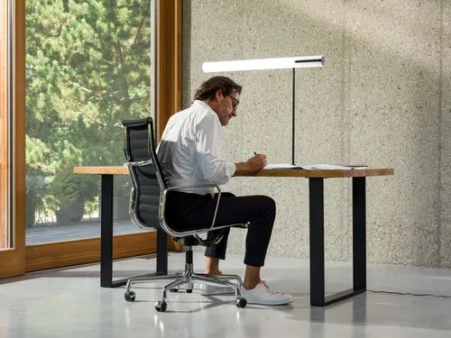 there is a man sitting at a desk with a lamp on