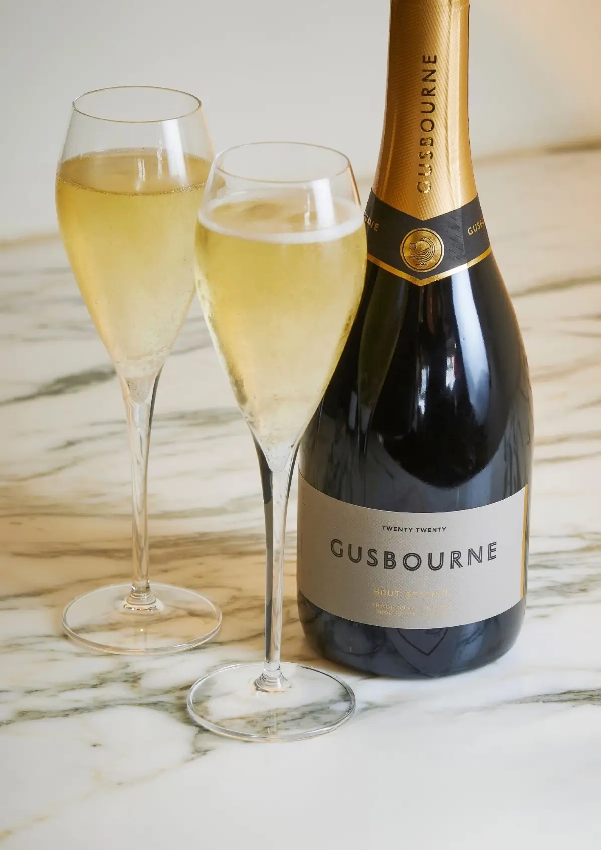 A bottle of Gusbourne Brut Reserve with two glasses of English sparkling wine