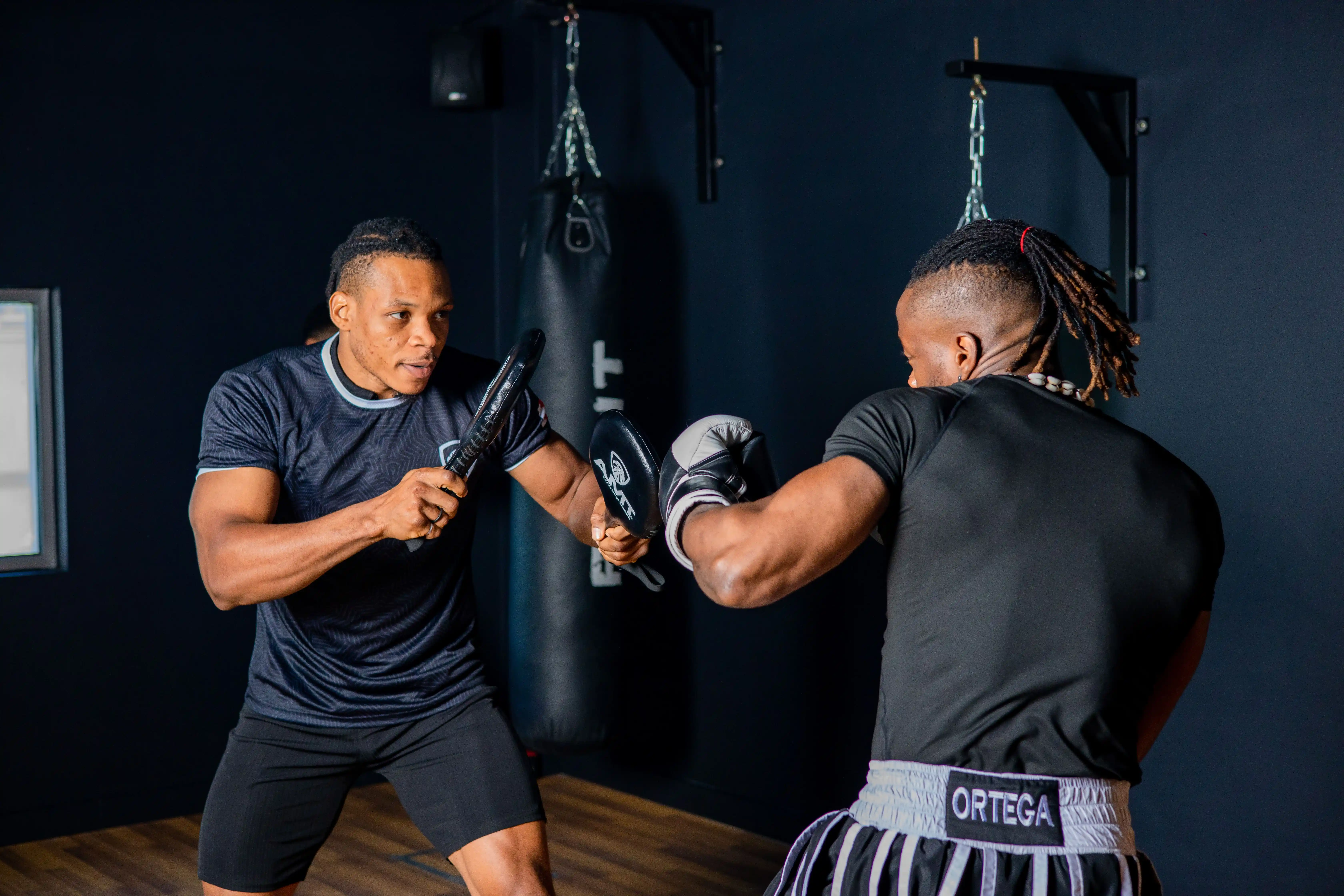 boxing coach doing pad work with trainee