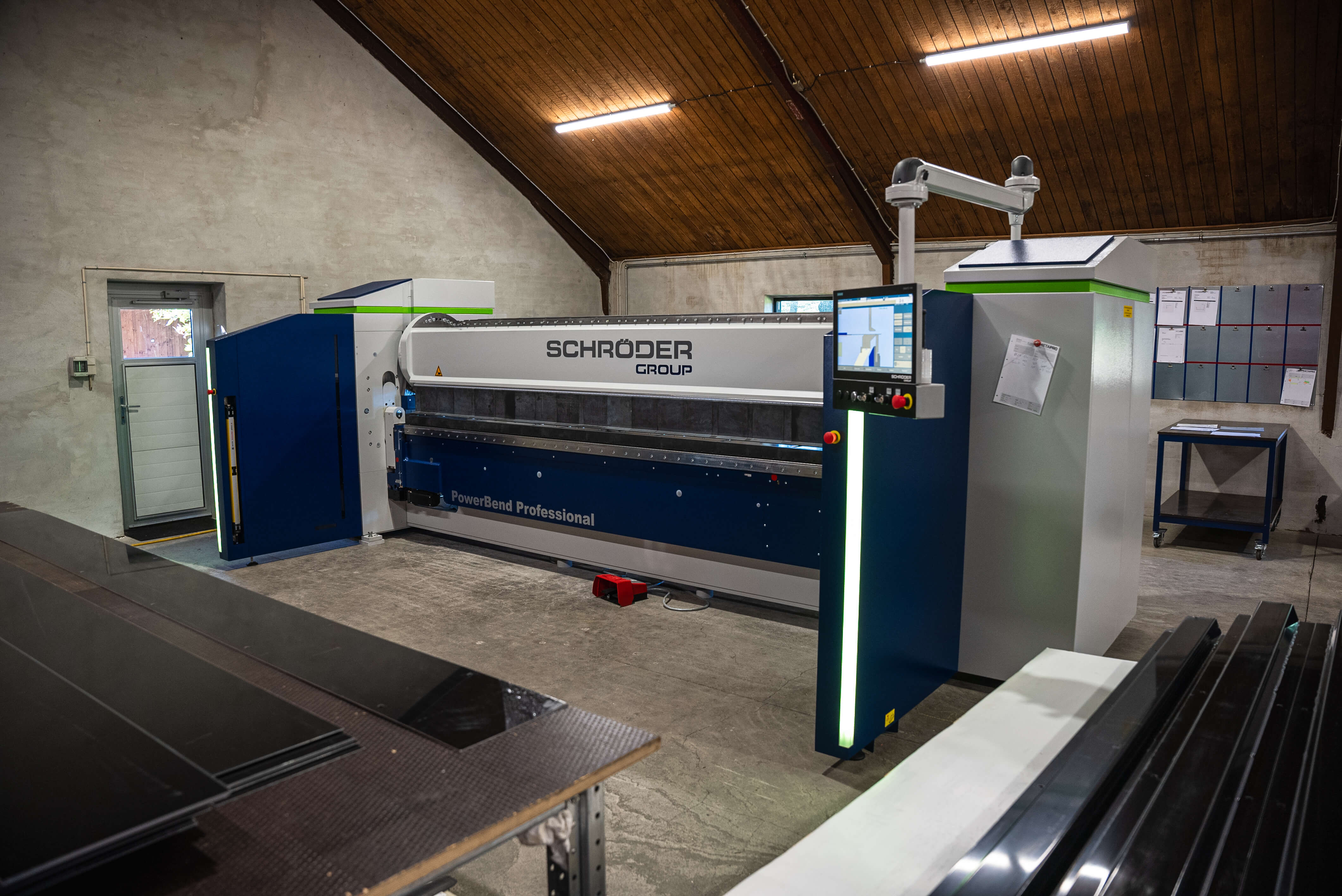 Schröder Group PowerBend Professional metal bending machine in an industrial workshop with wooden ceiling and concrete floor.