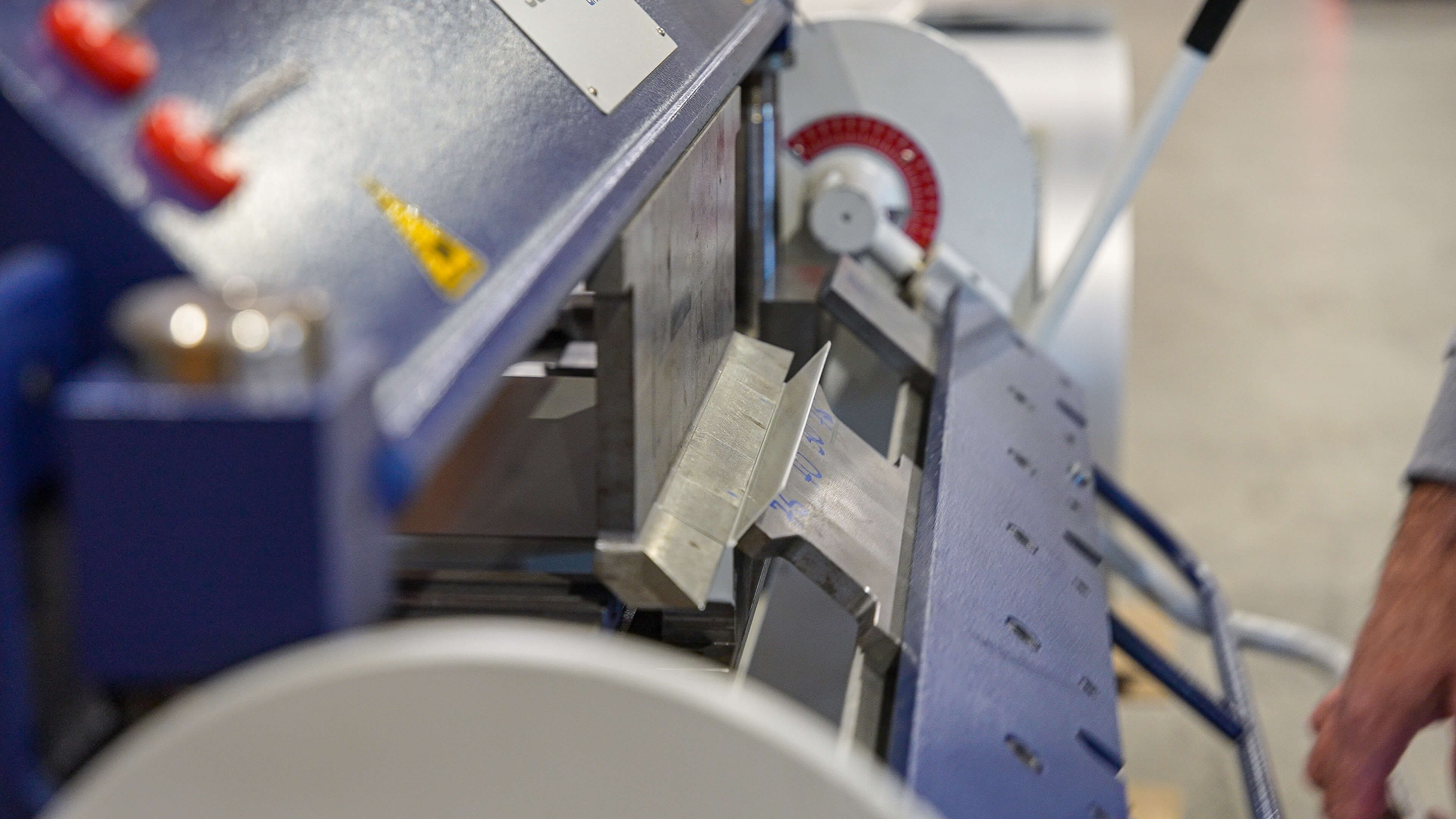 Close-up of a metal bending machine pressing a sheet of metal at an angle.