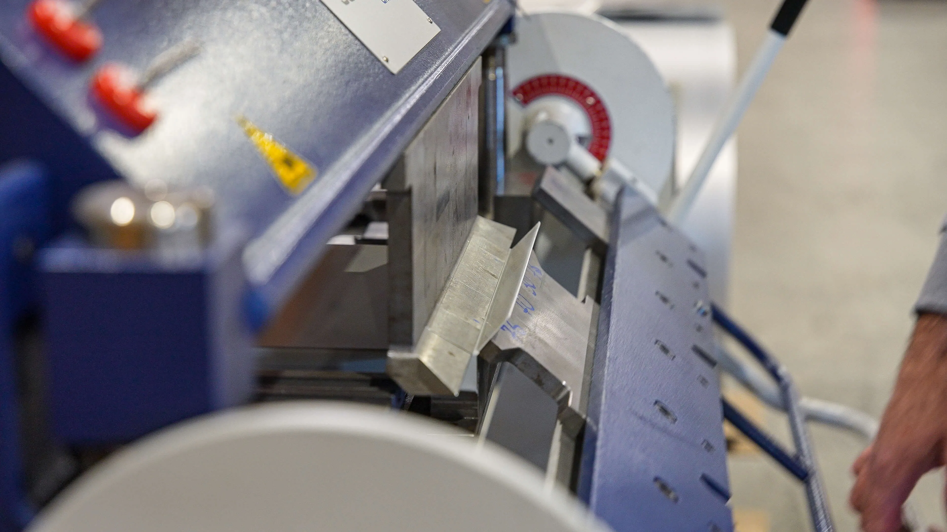 Close-up of a metal bending machine pressing a sheet of metal at an angle.