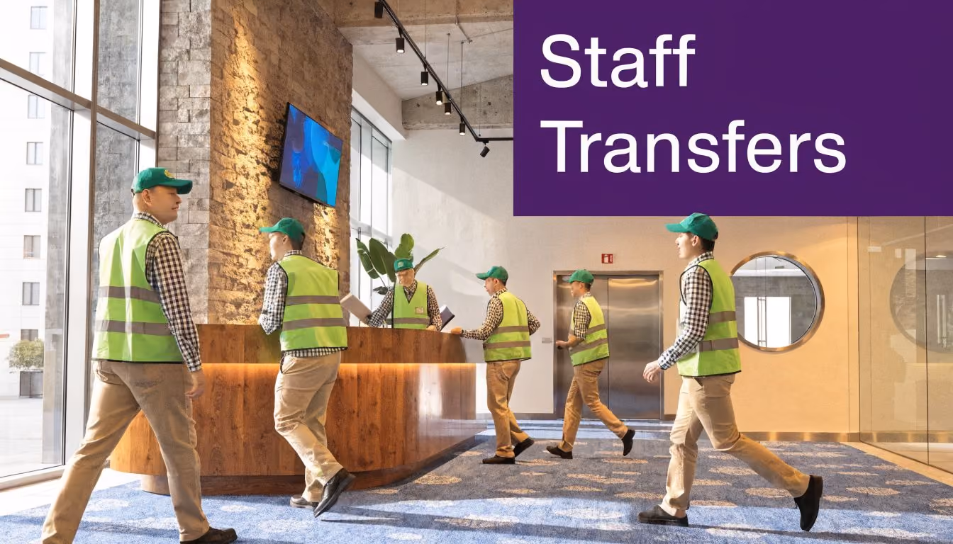 Several staff members wearing high visibility vests and green caps walking through a modern hotel lobby.