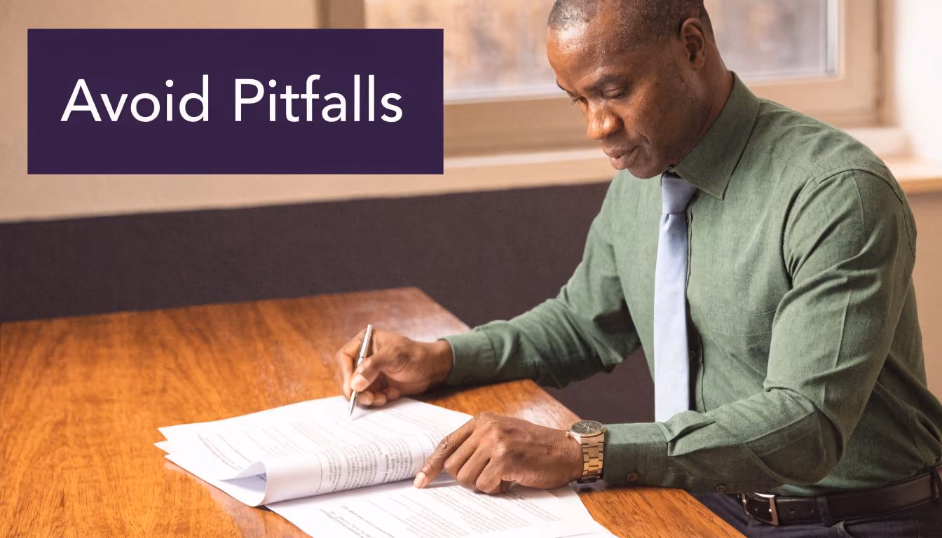 A professional man in a green shirt carefully reviewing and signing important business documents at a desk.
