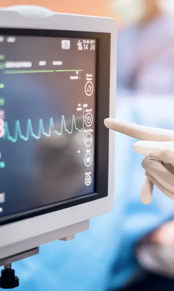 A person in white gloves points at a monitor.