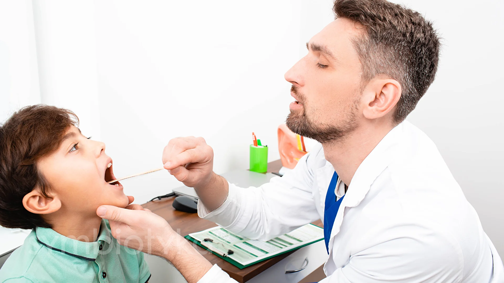 A man brushing the teeth of a young boy.