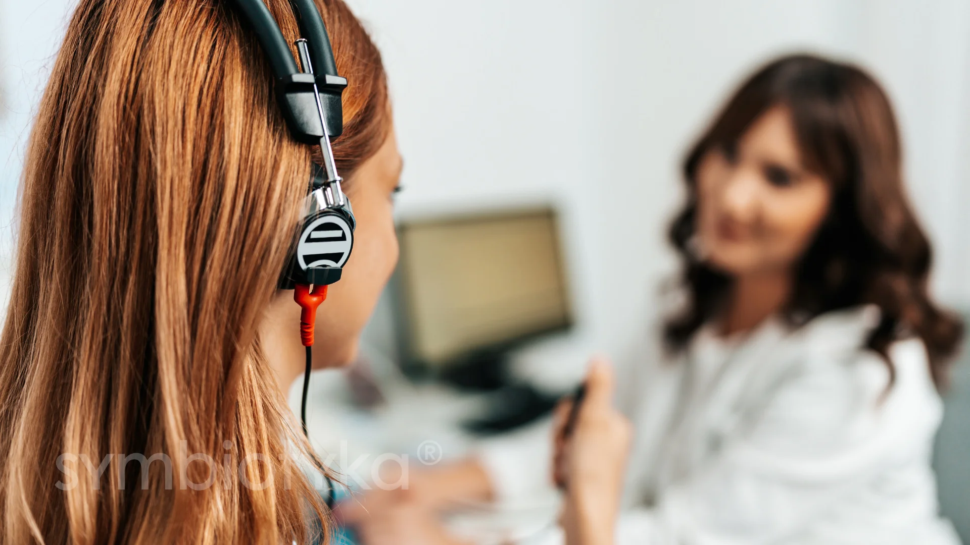 A woman wearing a headset talking to another woman.
