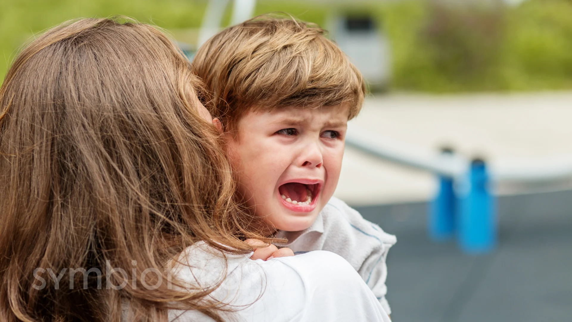 A young boy is holding a young girl in his arms.