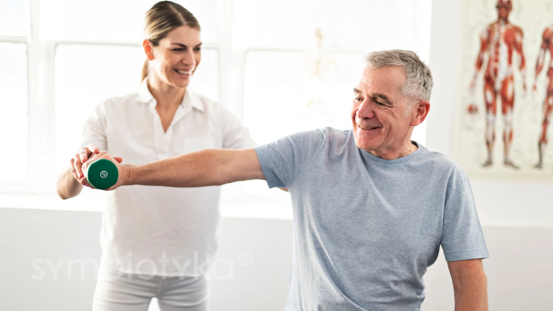 A man holding a green dumb with a woman in the background.