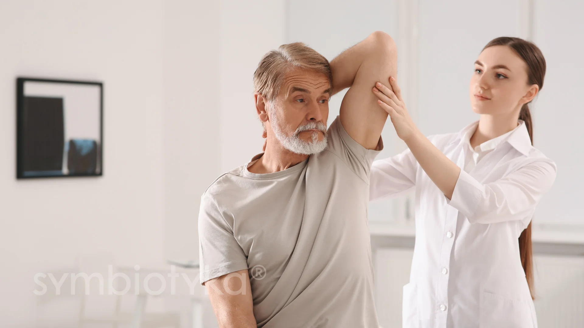 A woman helping a man put on his shirt.