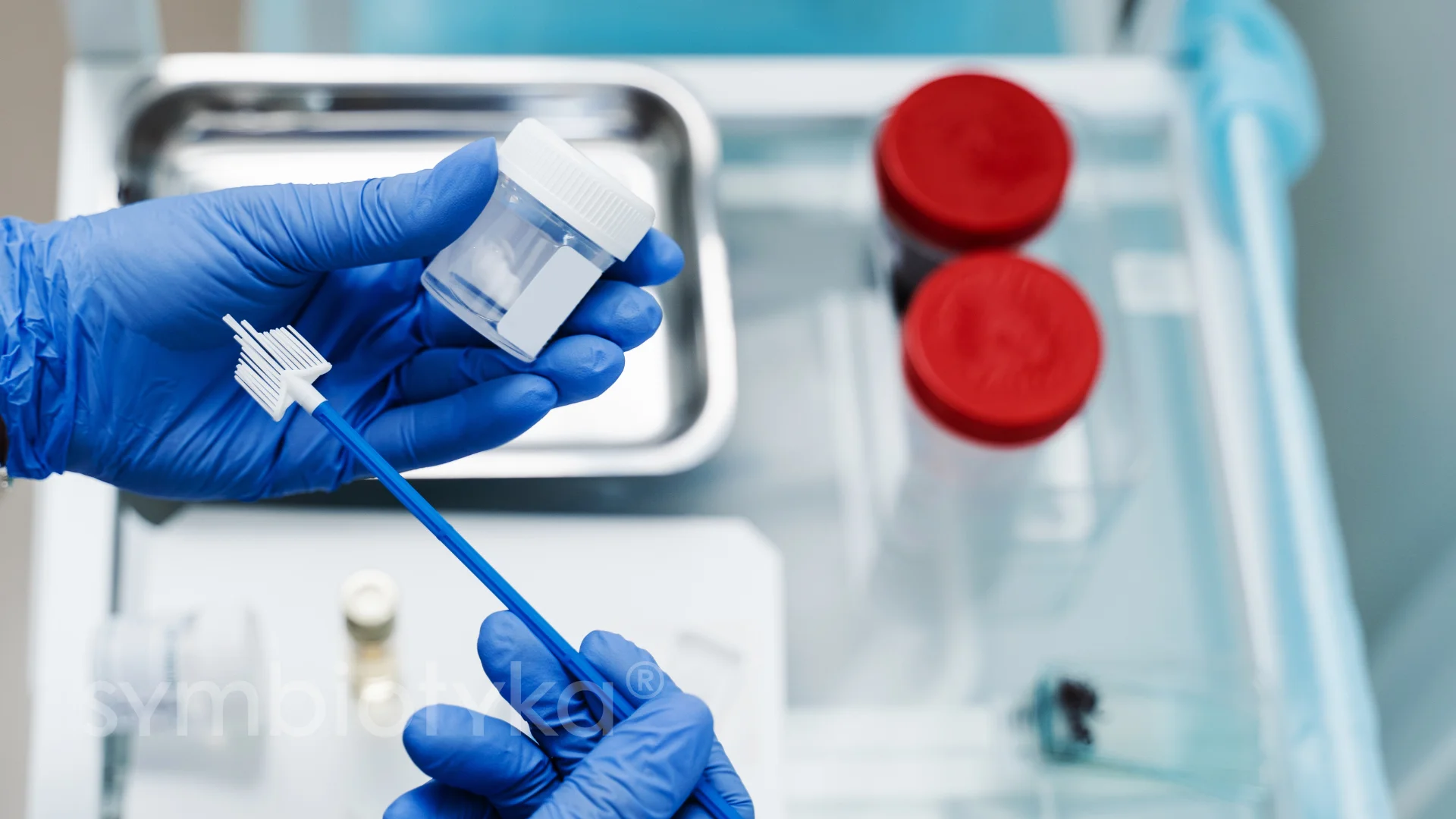 A person in blue gloves holding a toothbrush.