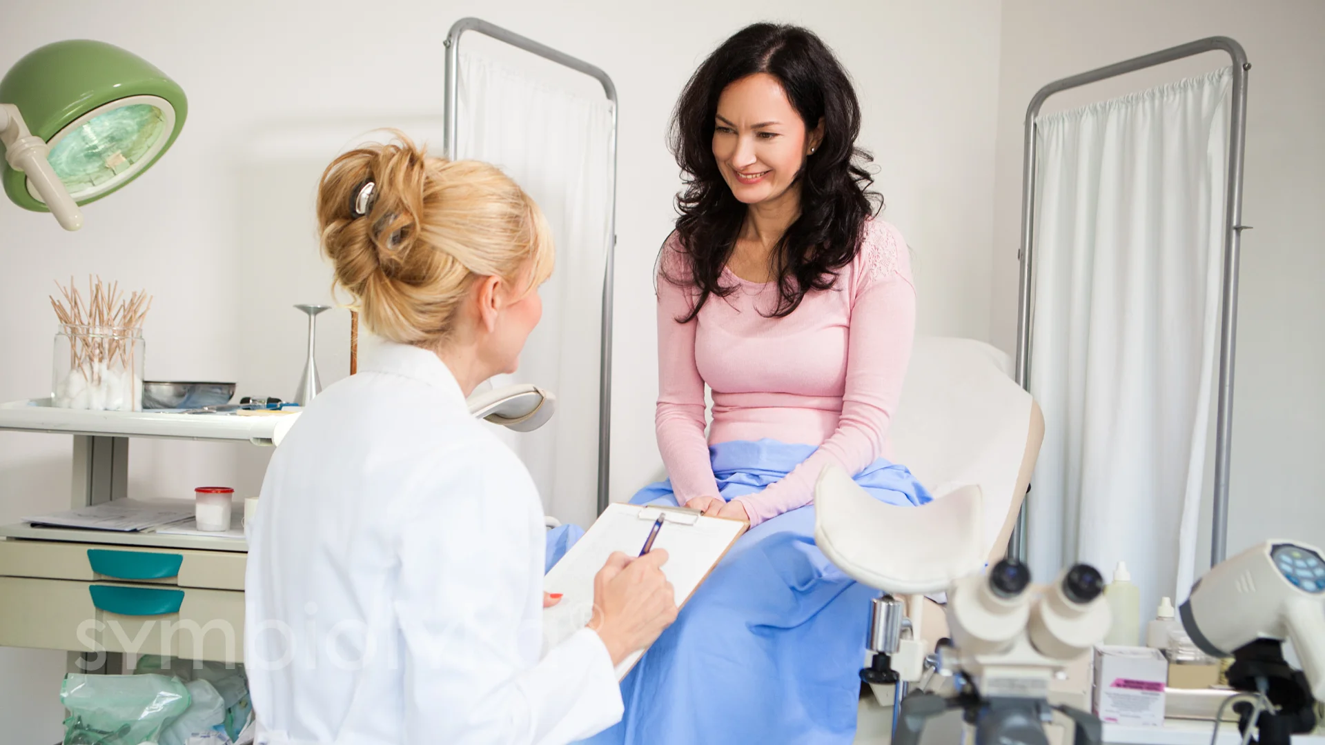 A woman sitting in a chair talking to a doctor.