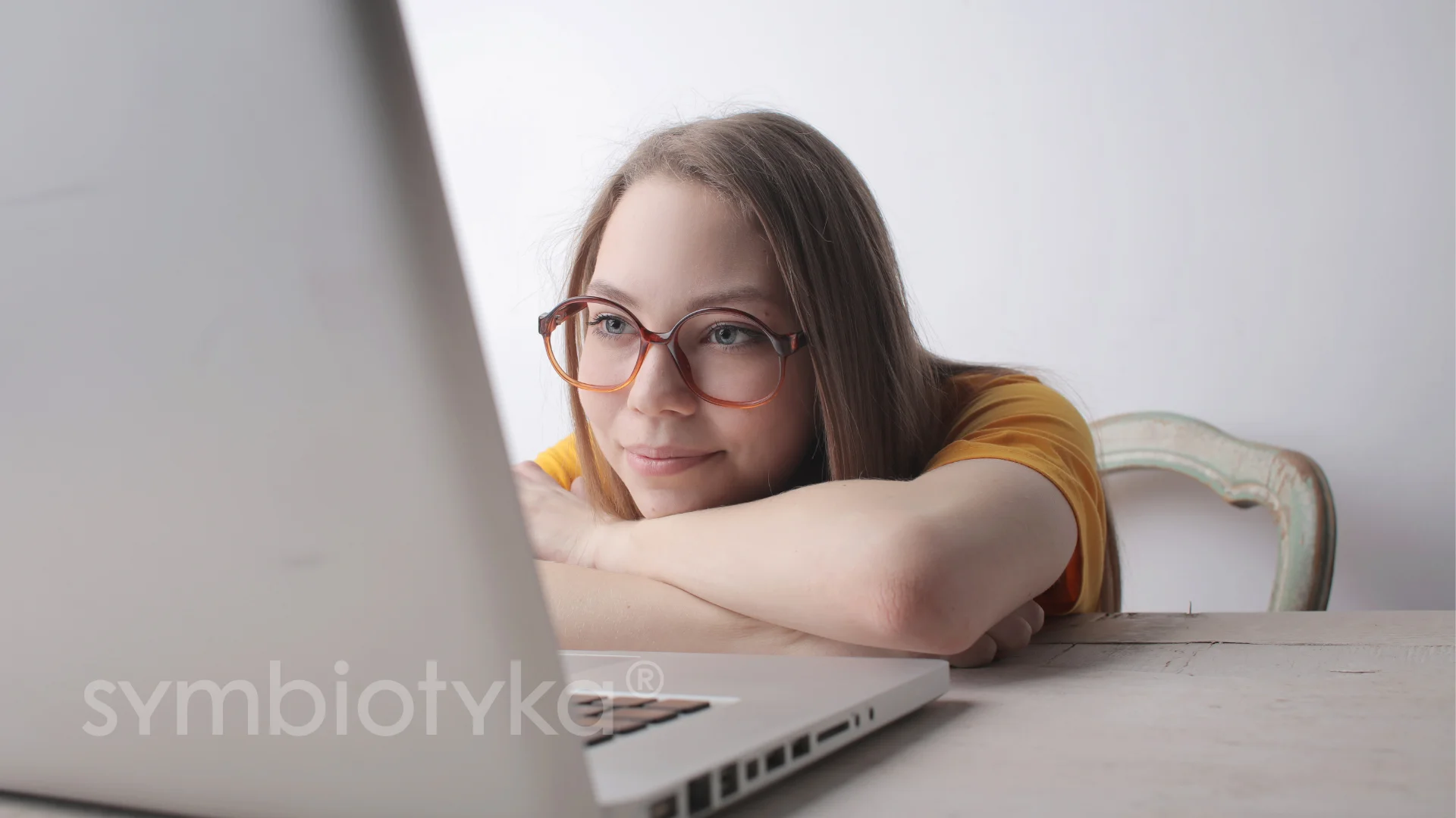 A woman with glasses is looking at a laptop.