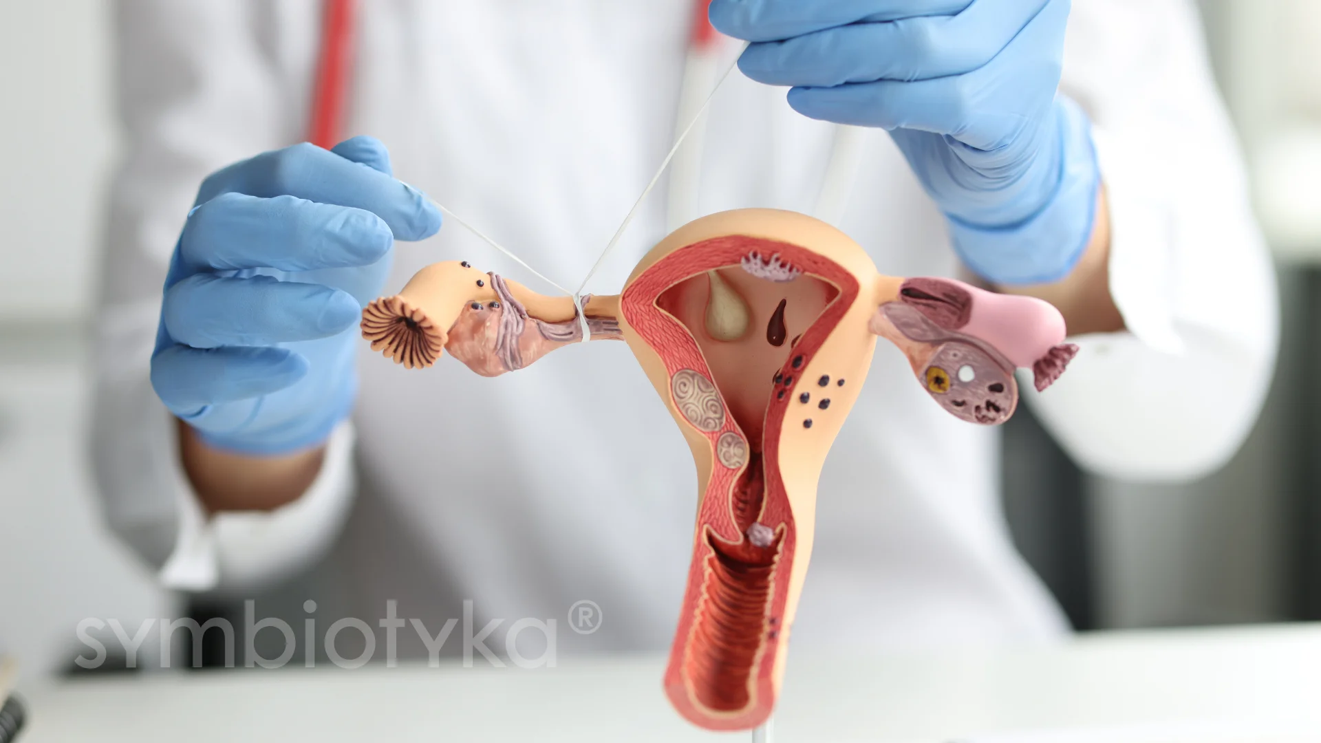 A person in blue gloves holding a model of a utensil.