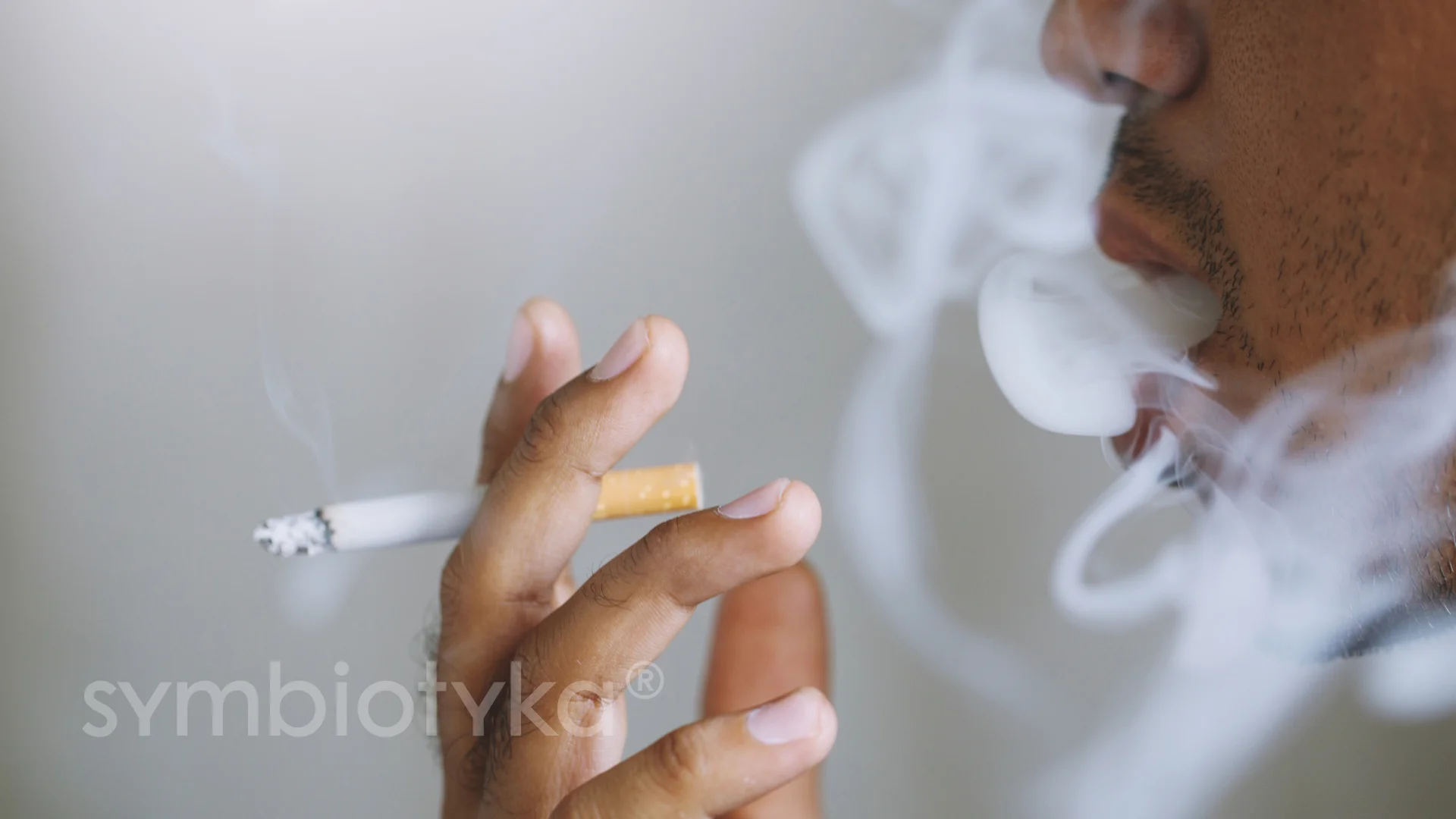 A man smoking a cigarette in front of a mirror.