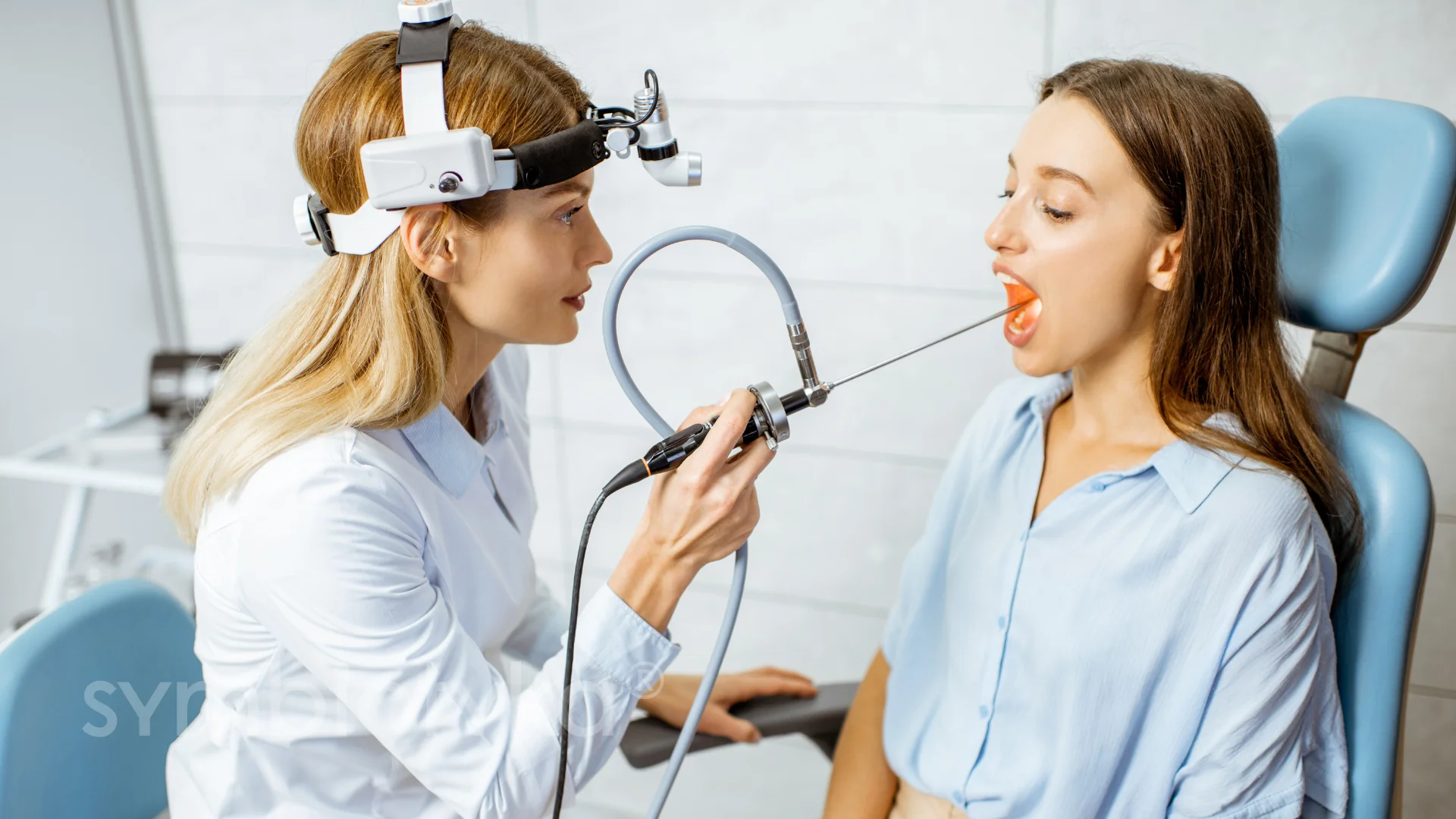 A woman getting her teeth brushed by a dentist.