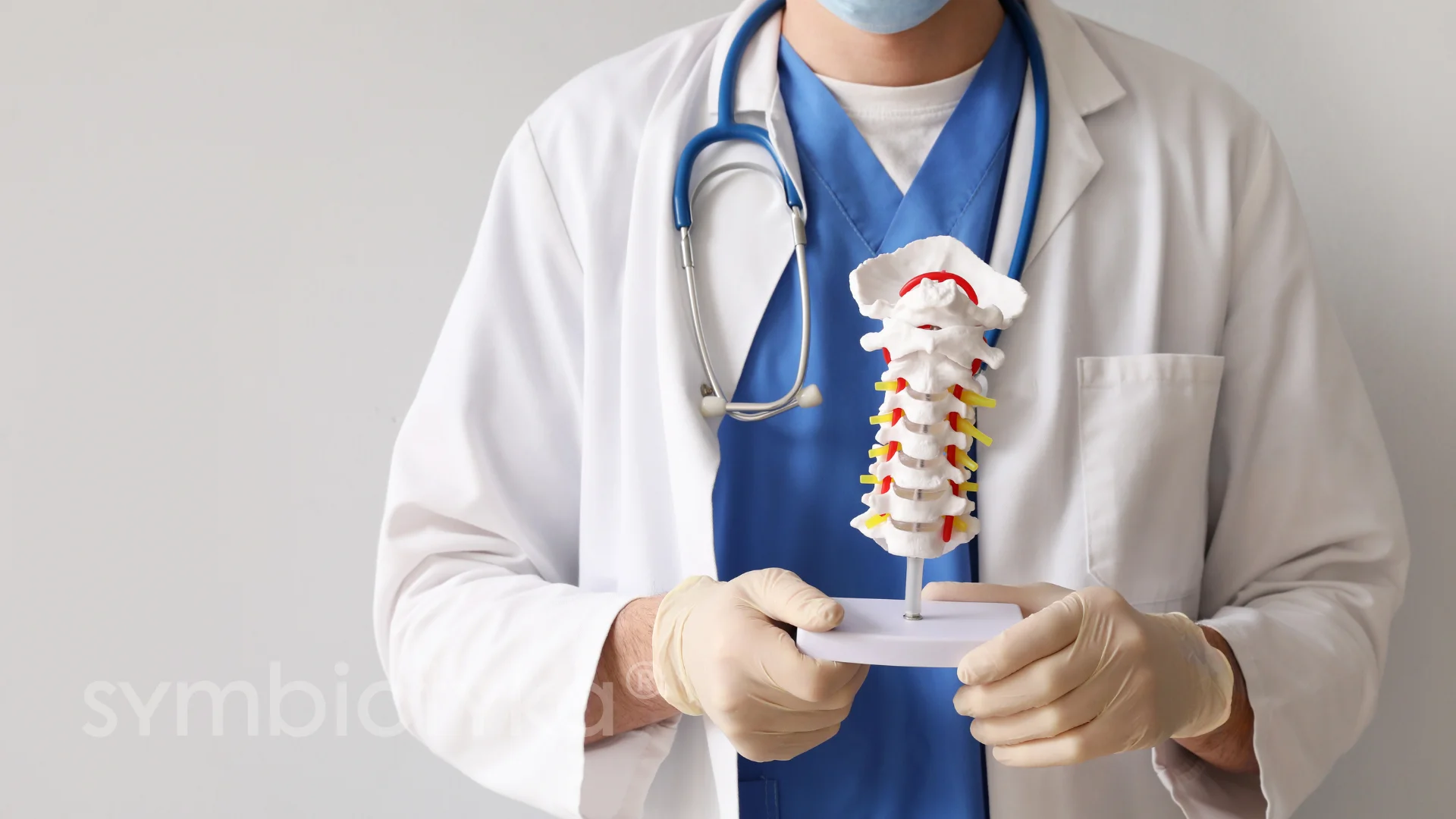 A doctor is holding a model of a skeleton.