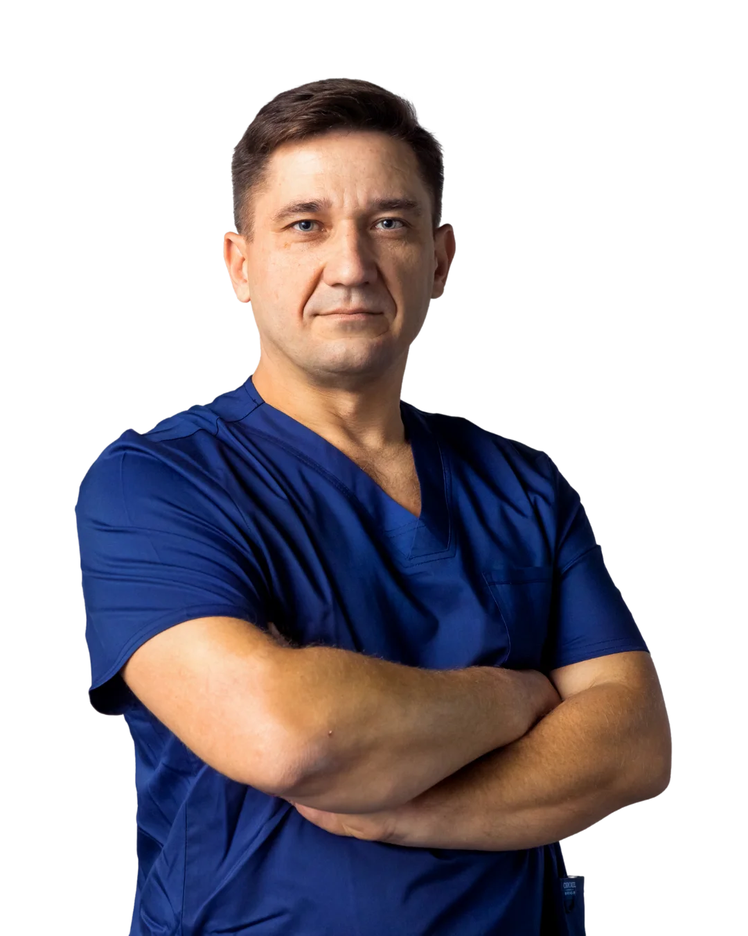 A man in a blue scrub suit with his arms crossed.