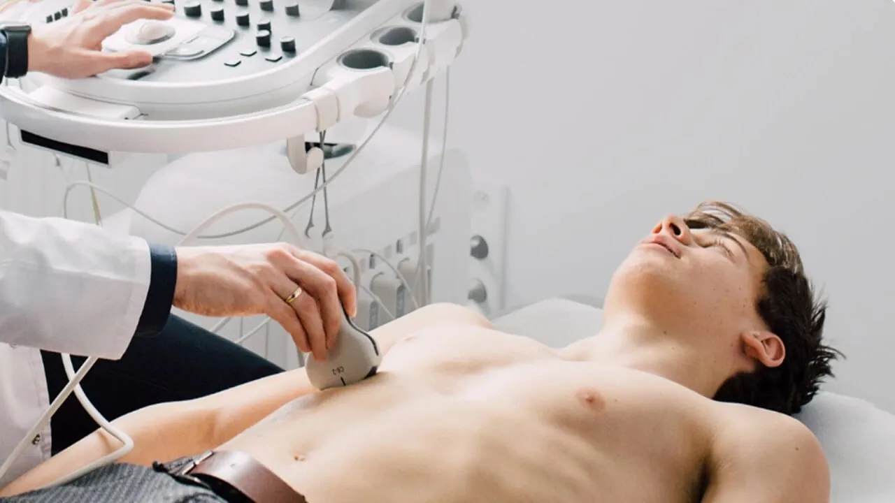 A man laying in a hospital bed being examined by a doctor.