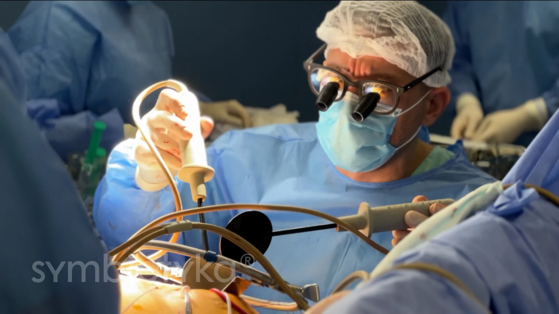 Surgeon wearing magnifying glasses, mask, and surgical cap performing a detailed surgery with medical instruments.