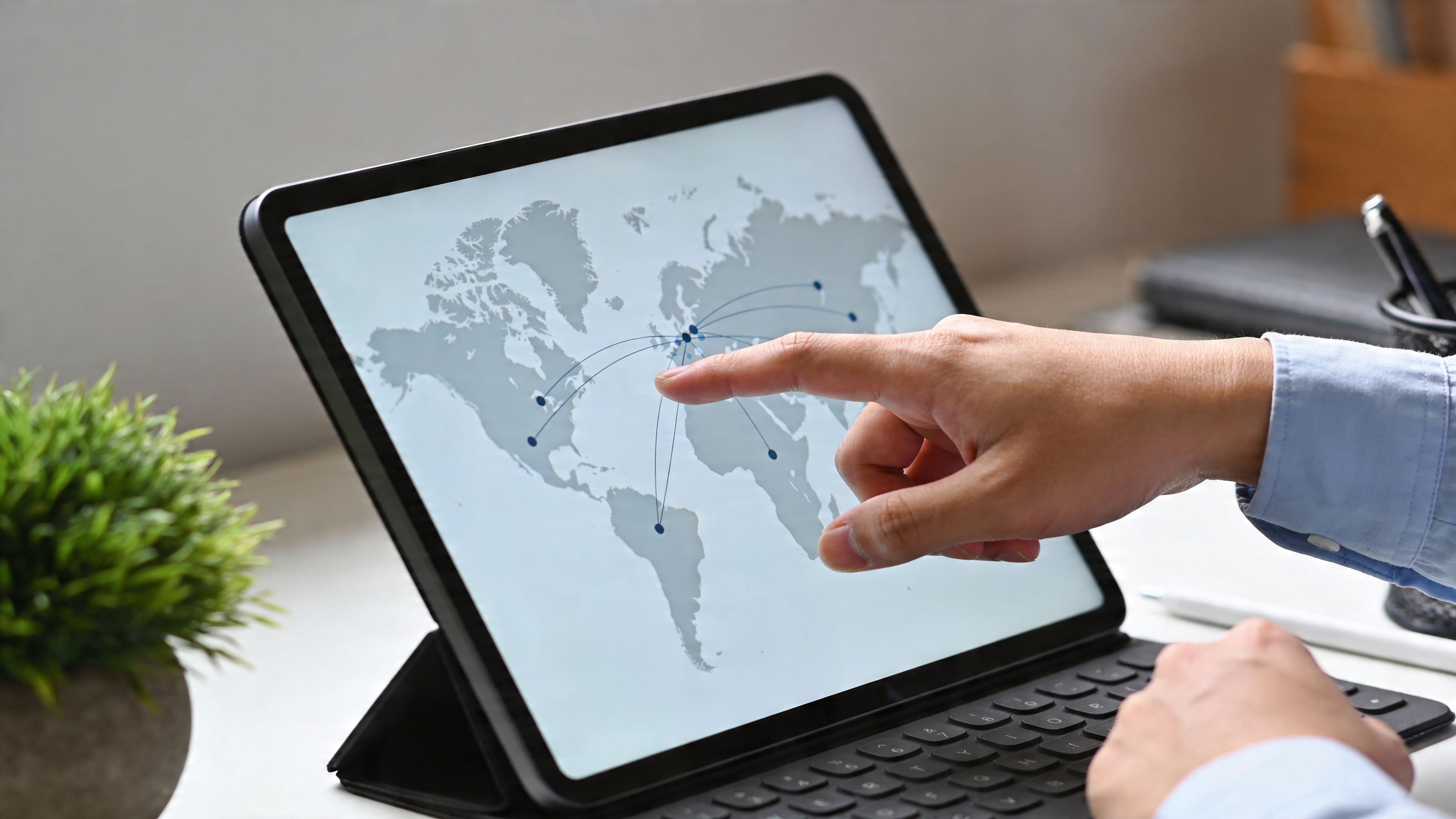 Una persona señalando un mapa mundial interactivo en la pantalla de una tableta electrónica en una oficina.