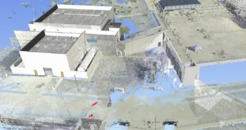 3D point cloud data of an urban area featuring a large white building with a flat roof at the center-left.