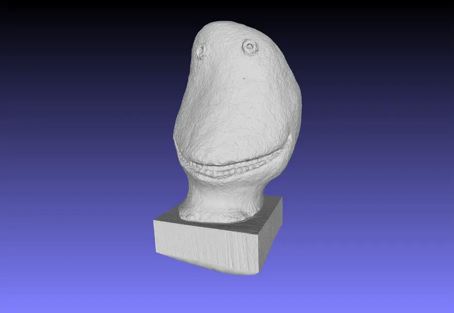 3D mesh model of a head-like structure with a textured surface, mounted on a rectangular base.