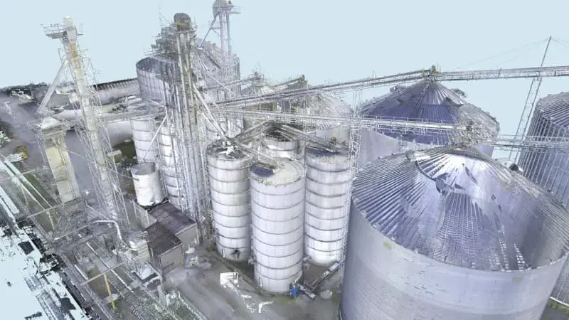A point cloud rendering of an industrial facility showing multiple large cylindrical storage silos and interconnected structural elements.