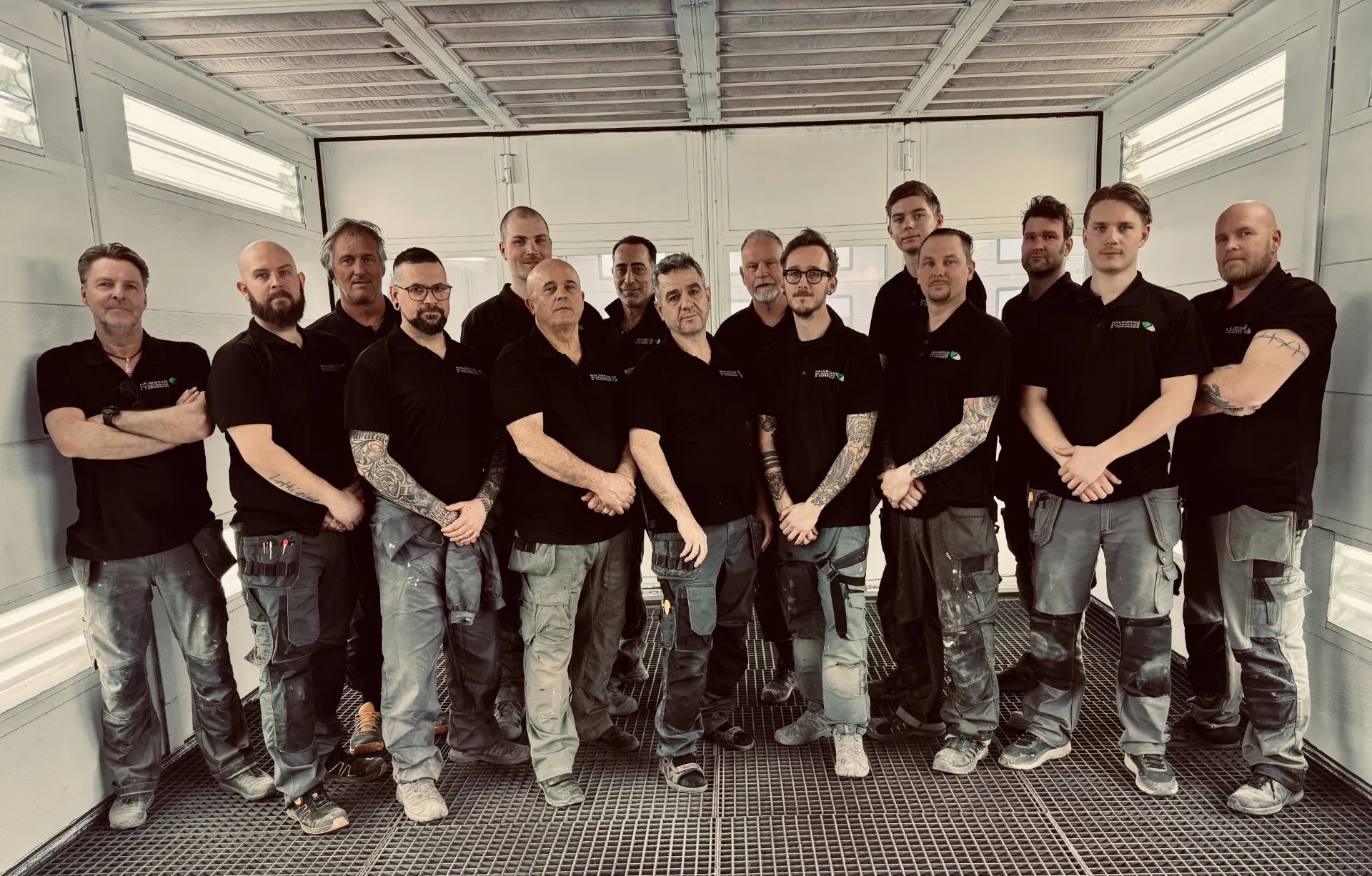 Teamet på Halmstad Billackering i en gruppbild i verkstaden, porträttbild.