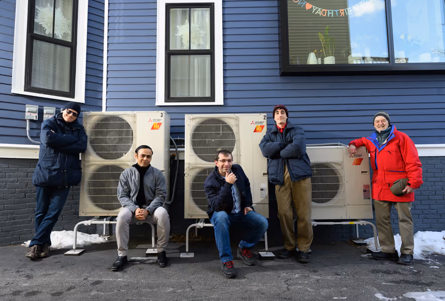 Five men standing outside, in front of home's AC units