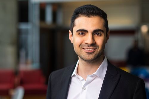 Portrait of Navid Azizan from the shoulders up, wearing a suit and tie, smiling.