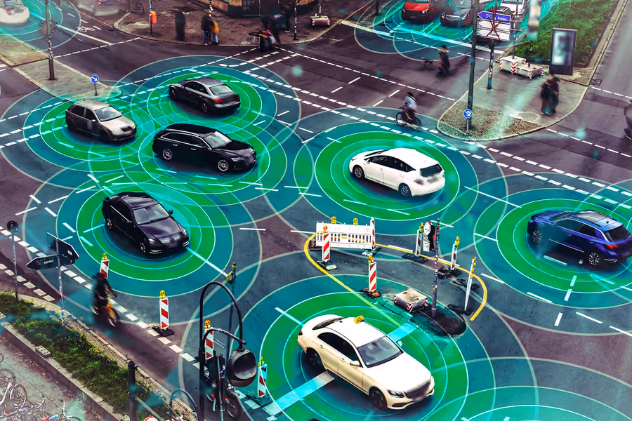 Cars at an intersection with futuristic sensors around them.