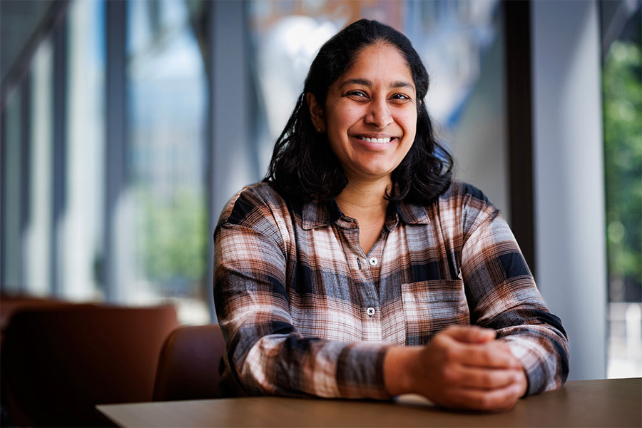  "A smiling woman with brown hair sitting behind a table with her hands clasped."
