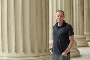 a photo of Martin Wainwright standing outside in front of large buildin columns