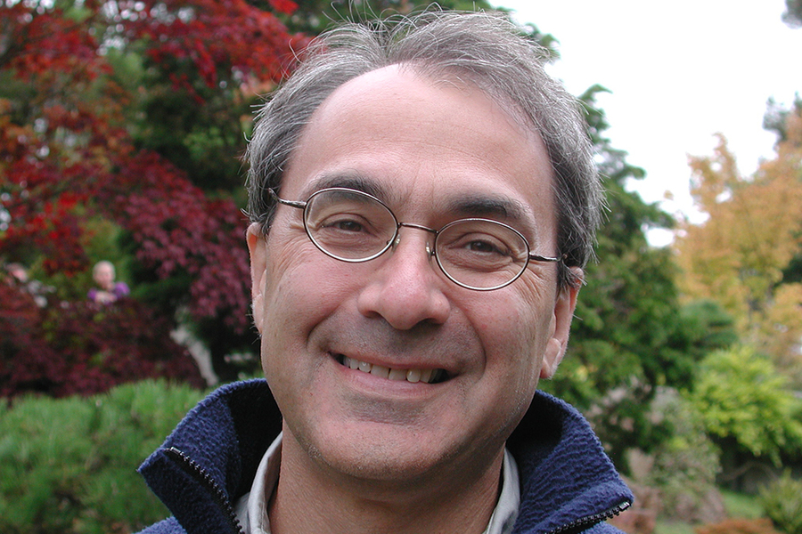 Headshot of Alfred Spector standing before trees with red, yellow, and green leaves