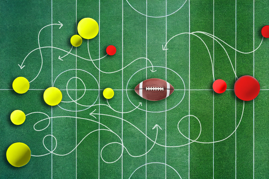 Yellow and red balls compete on an AI-generated football field. Chalk lines show possible movement, and a football is in the middle.