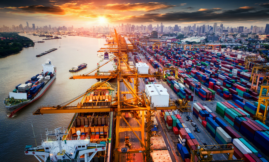 Photo of a busy port with ships being loaded and unloaded and thousands of containers waiting to be moved.