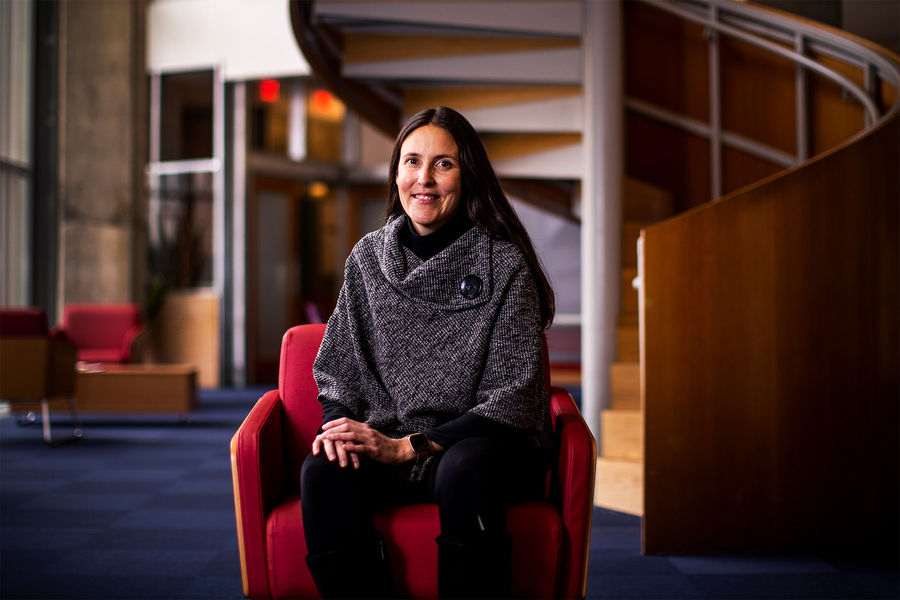 Caroline Uhler sits in front of the spiral staircase in the LIDS lounge