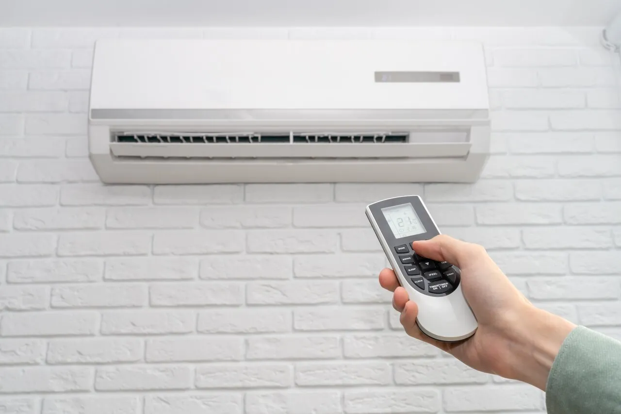 A close shot of hands using AC remote controller to control Ductless AC System