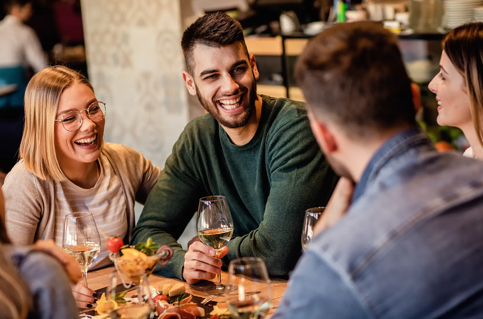 Group of friends having drinks and charcuterie laughing together