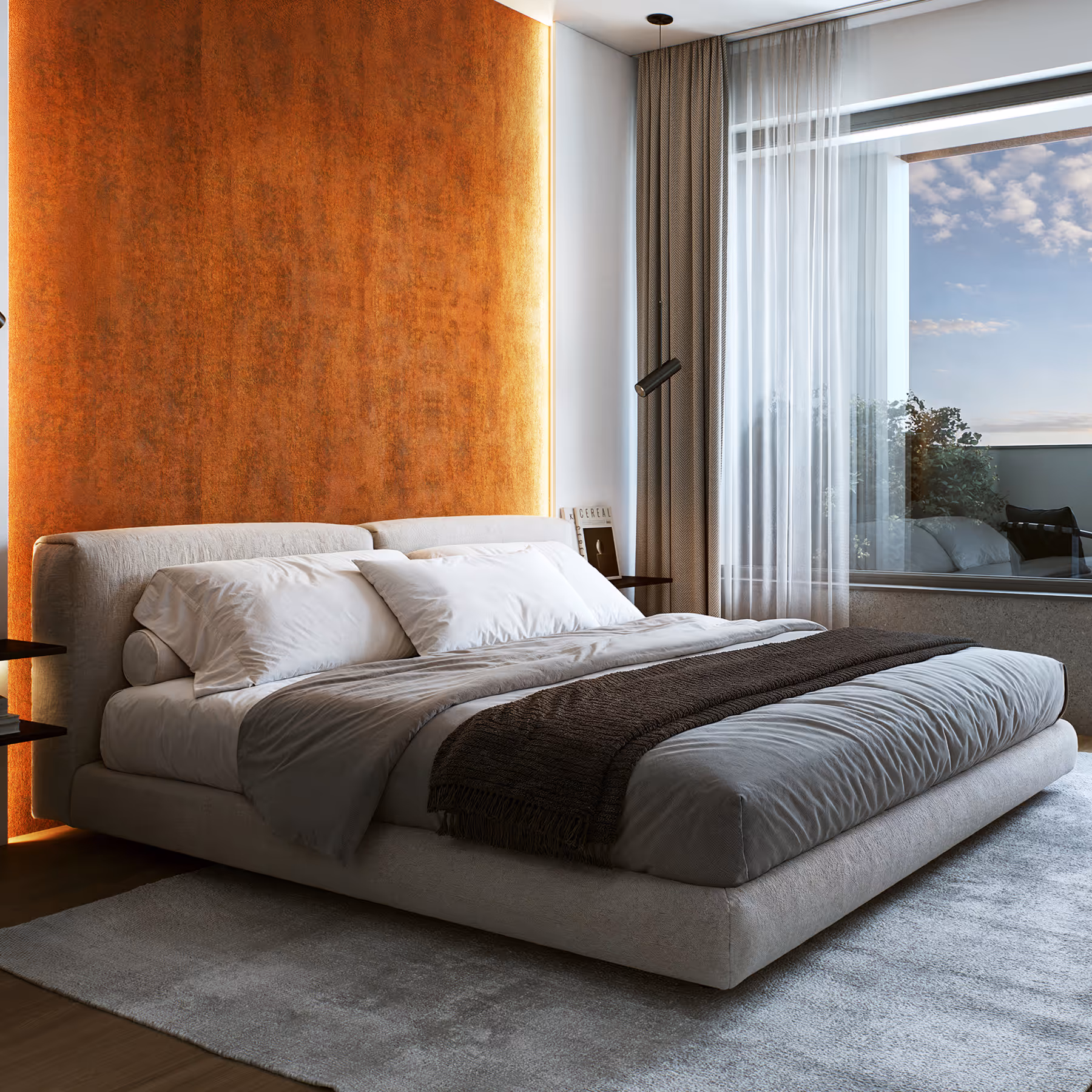 Moderní ložnice s velkou postelí s bílým prádlem a hnědým přehozem, osvětlená oranžovou zdí a velkým oknem s bílými závěsy.