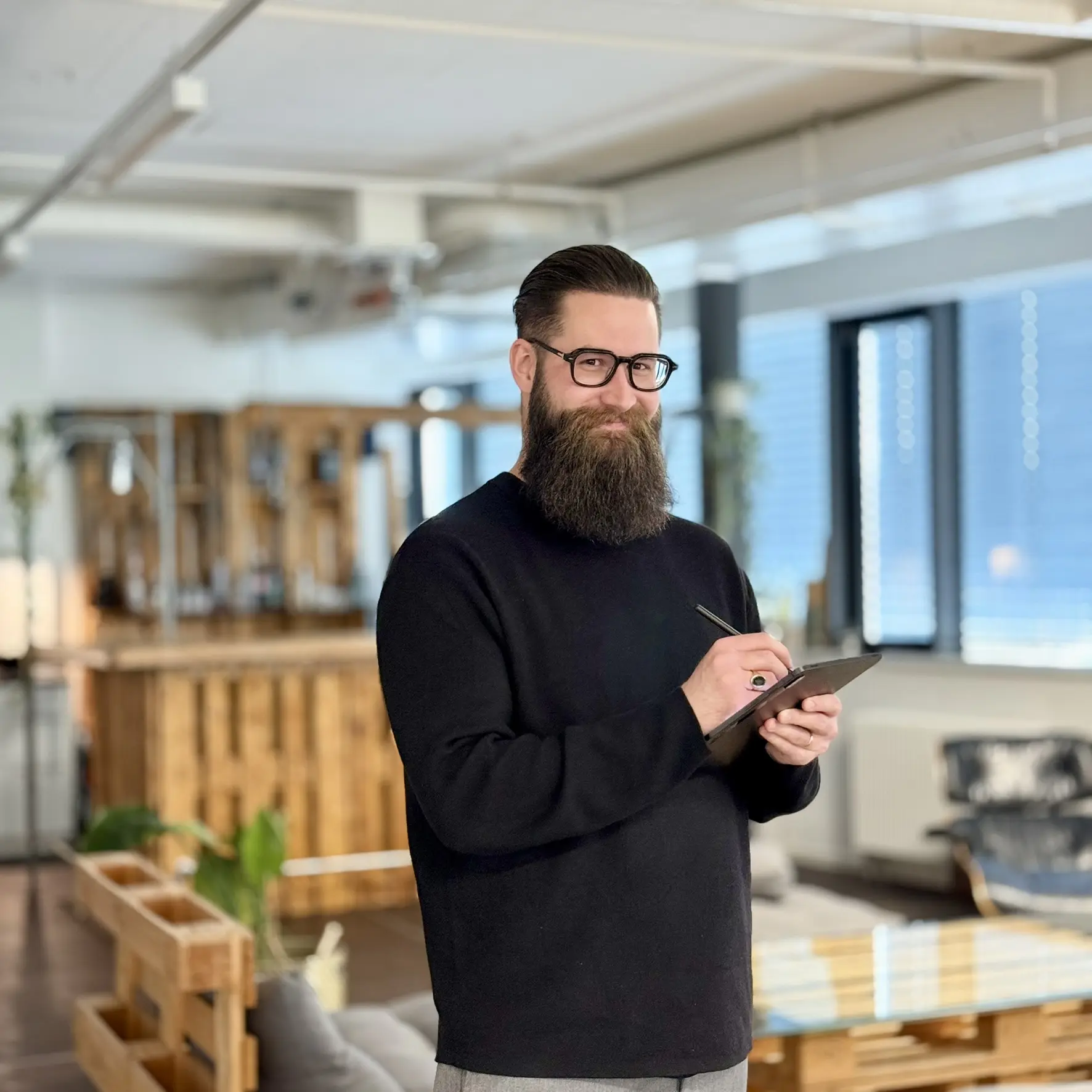 Portrait of Jonas Furer-Junker with tablet, smiling, holding a pen, looking at the camera