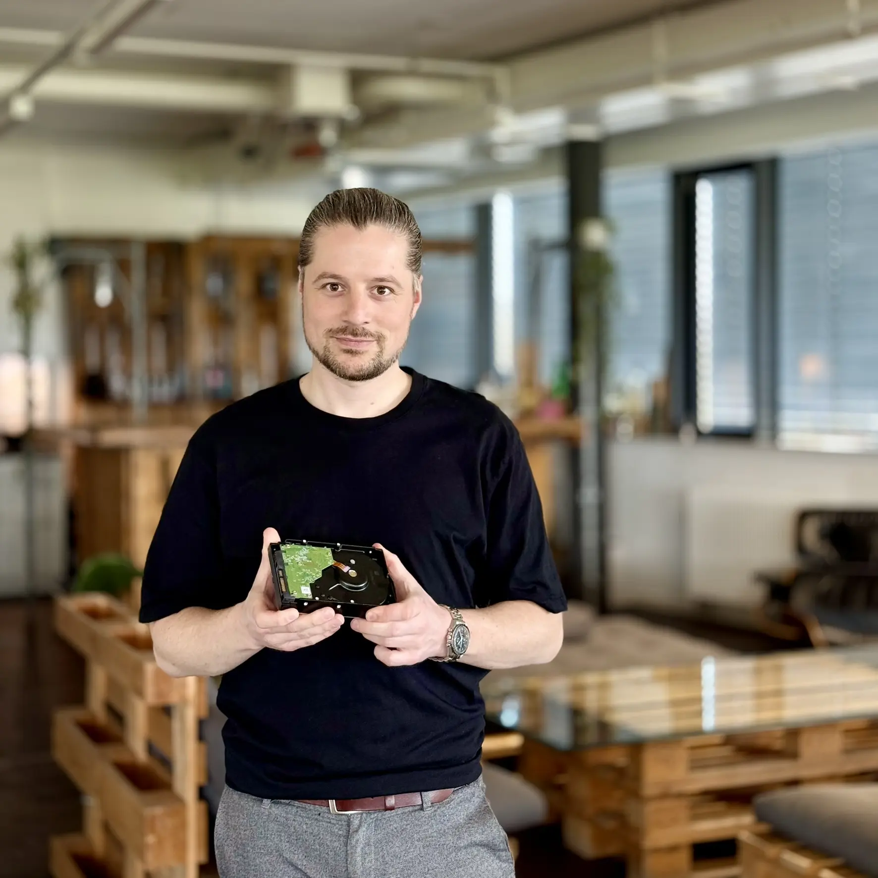 Photo Pascal Argast avec un disque dur, souriant à la caméra, arrière-plan flou