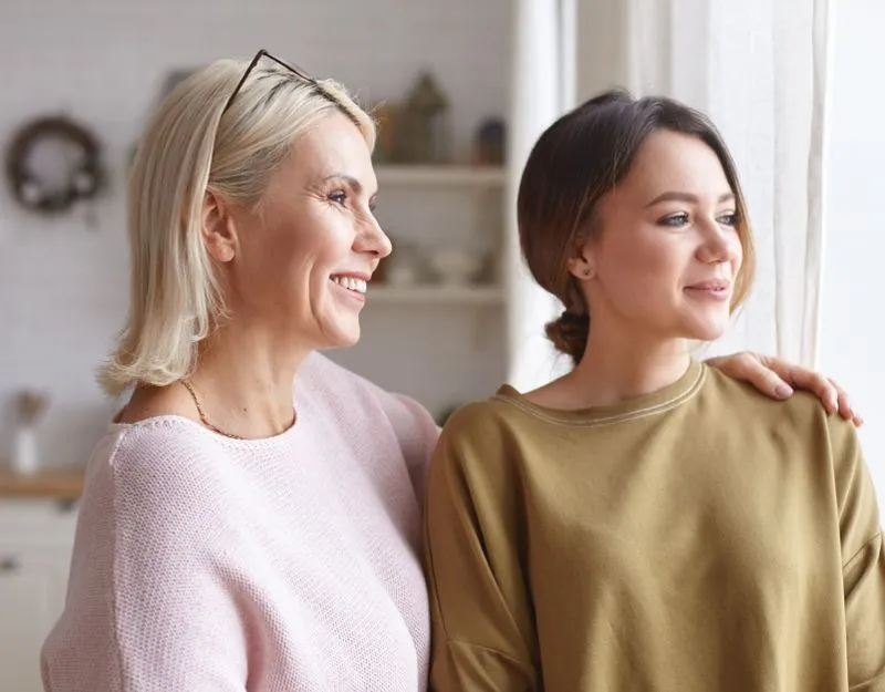 Mother with arm around teenage daughter's shoulder