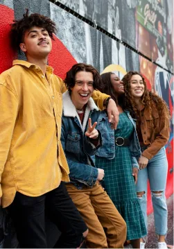 Four young people standing in front of mural