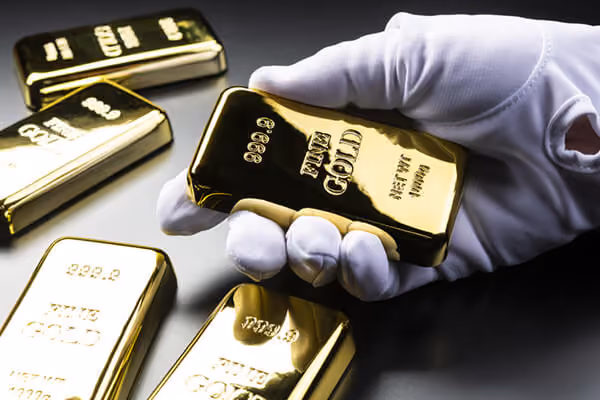 Gold bullion close-up, white glove hand holding bullion