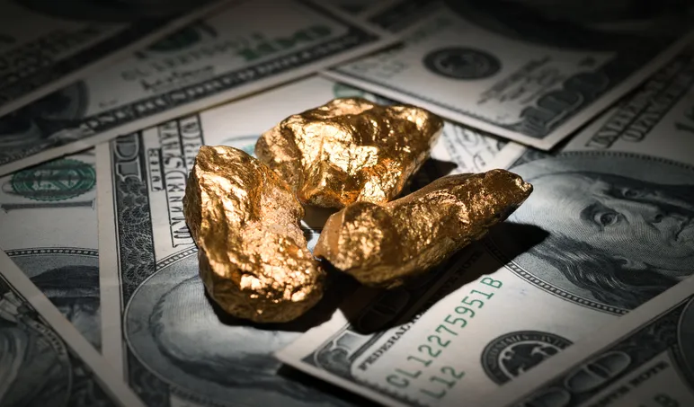 Close up shot of gold nuggets on one hundred dollar bills