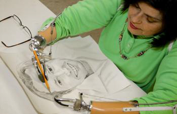 Becky Guinn painting a portrait drawing using her prosthetic arms