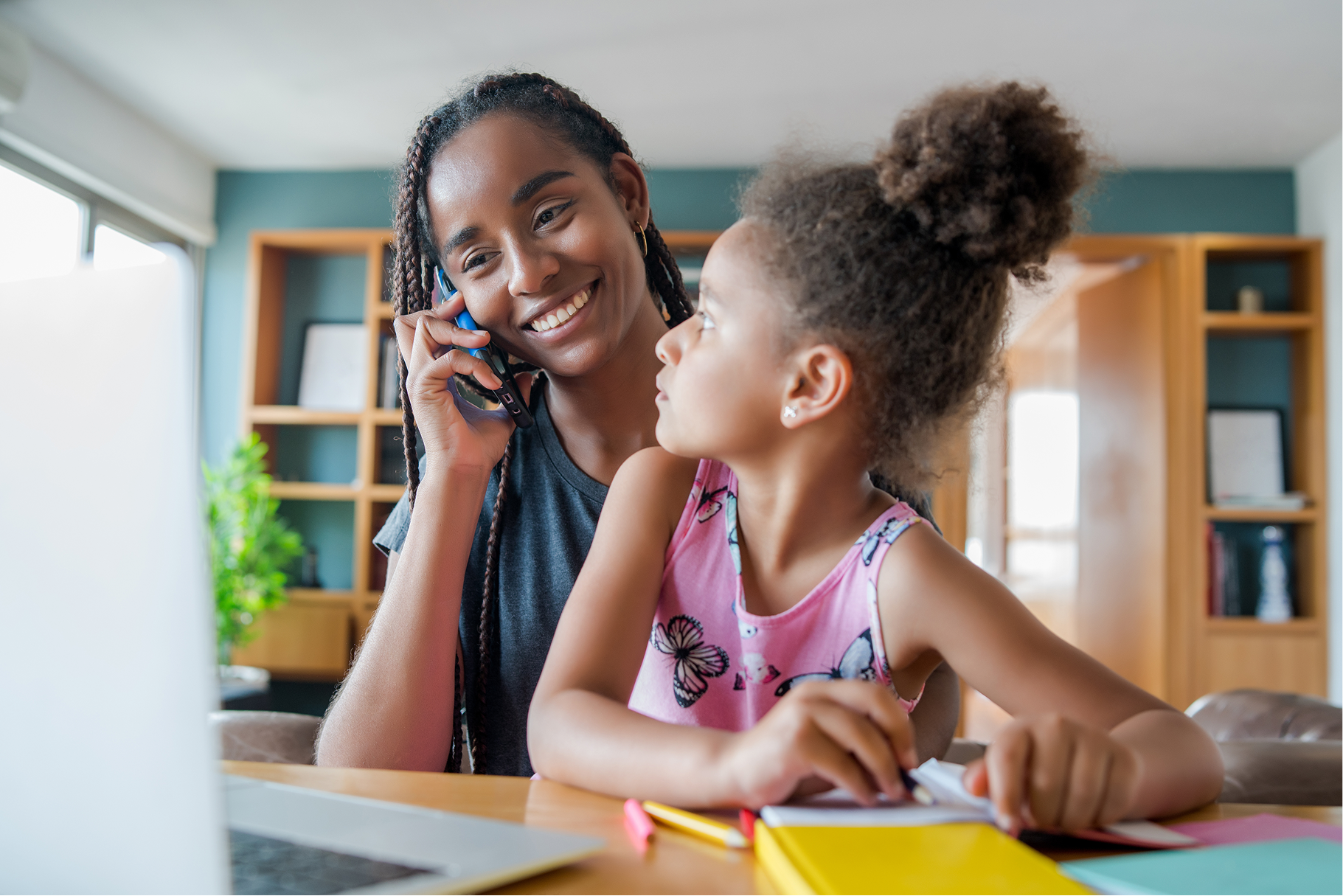 Smiling mother sitting on a desk with her daughter while on an introductory call with a certified feeding therapist.