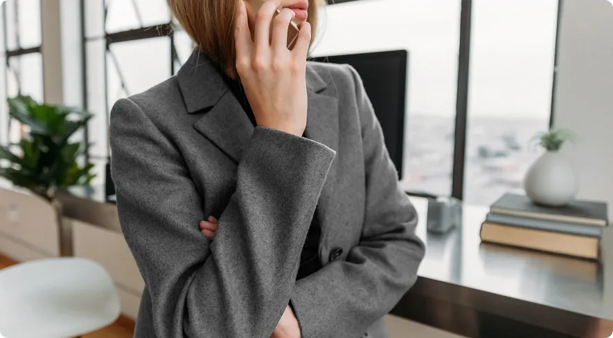 Retail manager in a grey blazer talking on the phone in an office